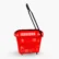 Side view of a red rolling shopping basket with four swivel wheels and a long black telescoping handle raised for pulling while walking.